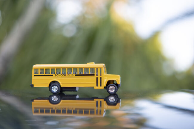 Model of classical American yellow school bus for transporting of kids to and from school every day. Concept of education in the USA. Taking children to school. 